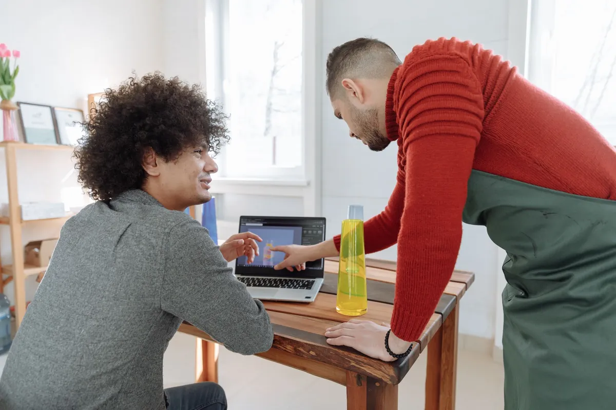 Two people go through something together on a laptop in a bright office