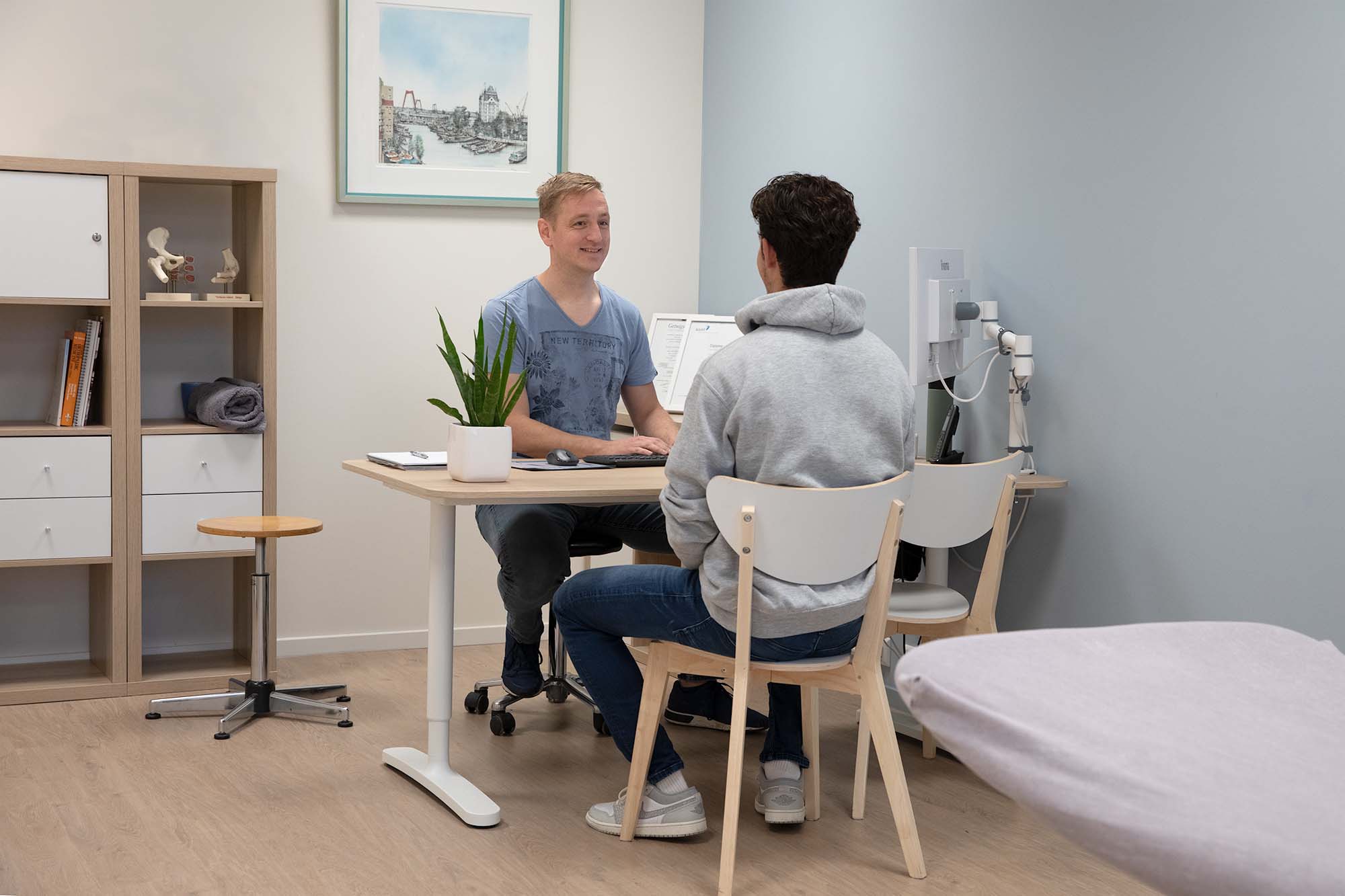 Physiotherapist in conversation with a patient in a treatment room